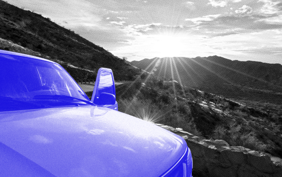 A blue car parked at a scenic overlook, representing the value and progress already made on the journey.